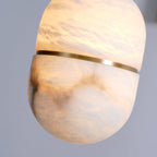Close view of this Clérachic pendant lit, the alabaster glowing warm and showing its cloud-like veining above and below the gold band.