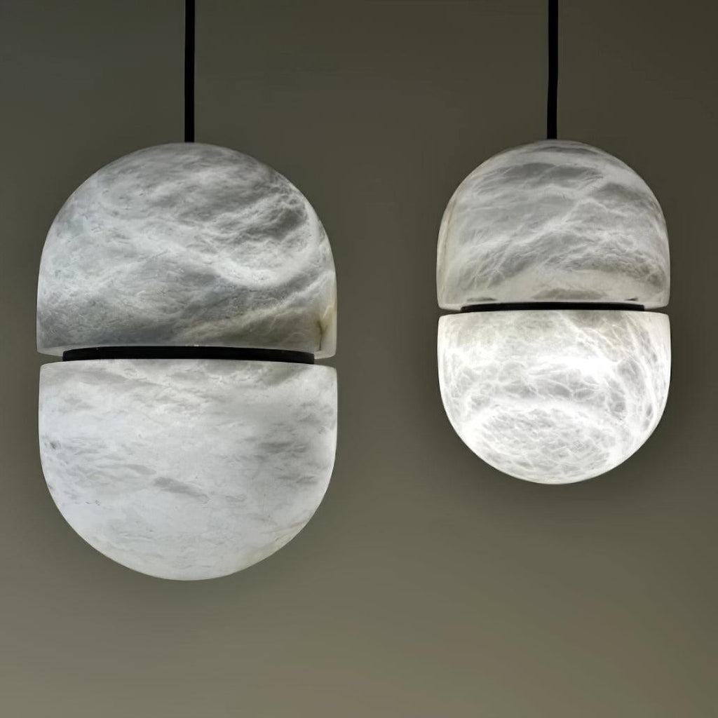 Two Clérachic alabaster pendants in a close view, with a dark band at the middle of each and a black cord above.