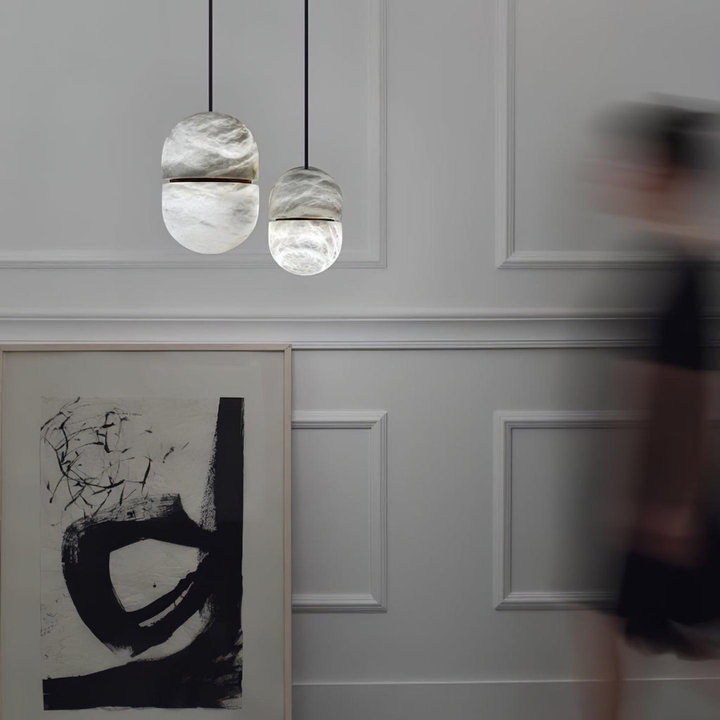 Two small Clérachic alabaster pendants on a pale panelled wall, with a large black-and-white abstract print below.