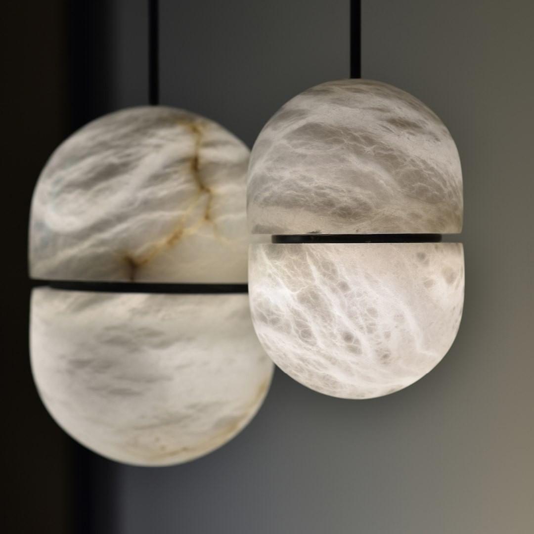 Close view of two Clérachic alabaster pendants with dark bands, the stone glowing with brown and white veins.