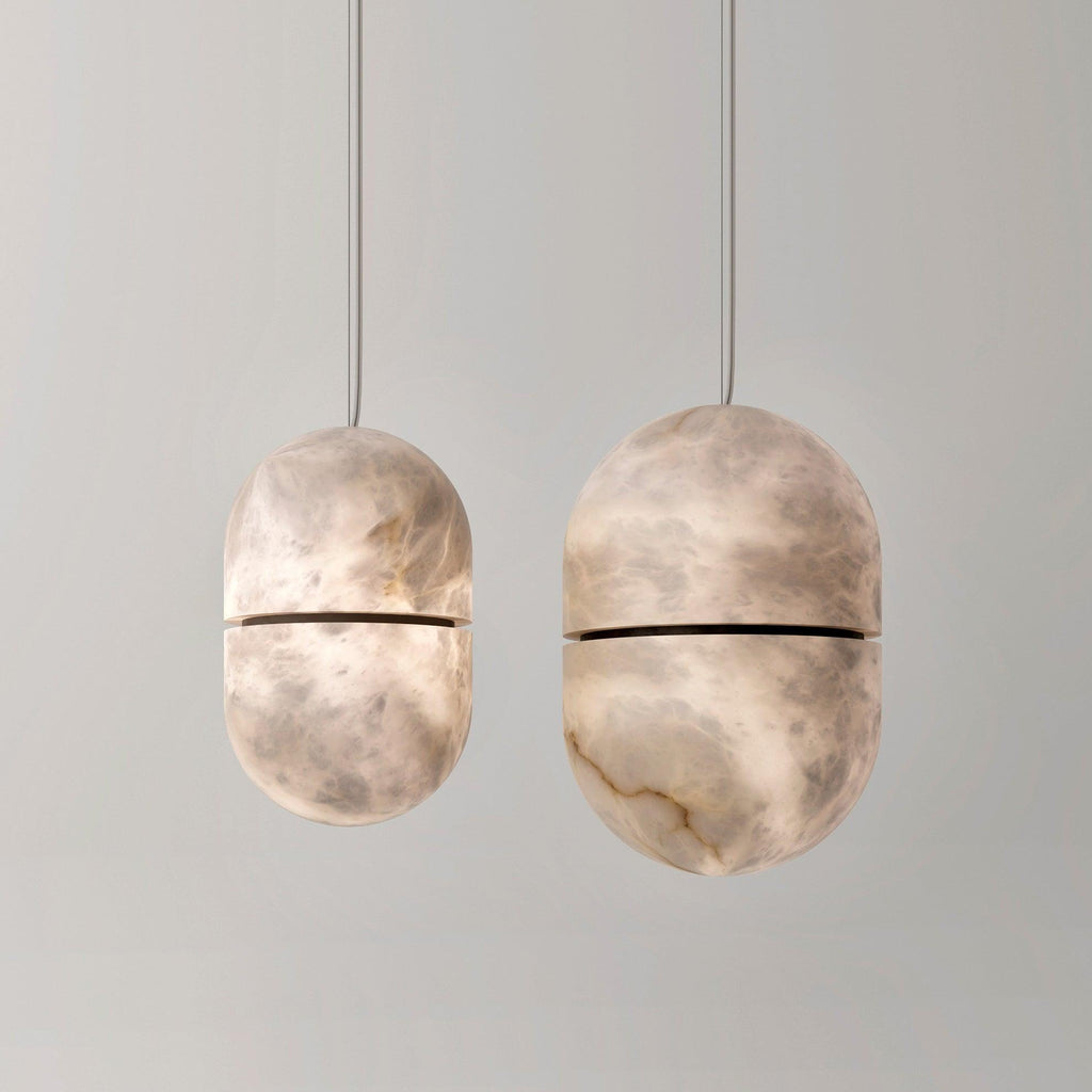 Two Clérachic alabaster pendants of different sizes on a pale grey backdrop, their dark bands and veined stone clear to see.