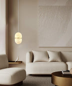This Clérachic alabaster pendant glowing in a soft neutral room, with a boucle sofa, a textured artwork and a round brass table.