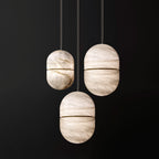 Three Clérachic alabaster pendants at different heights on a dark backdrop, each with a thin gold band and visible veining.