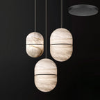 Three Clérachic alabaster pendants with dark bands, hung at different heights from a black round canopy.