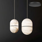 Two Clérachic alabaster pendants with dark bands beside each other on a dark backdrop, with a black canopy shown top right.
