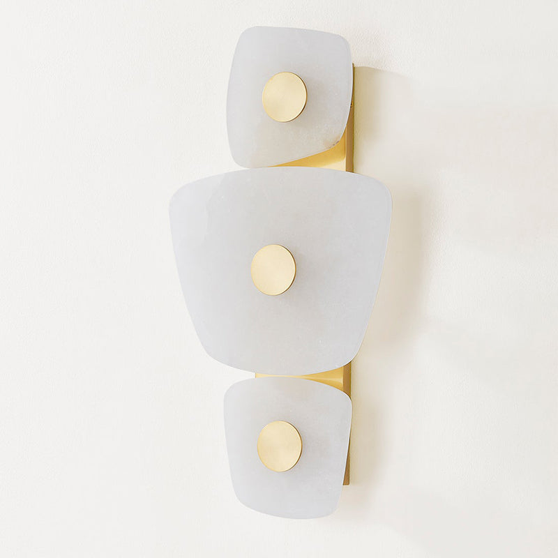 Unlit Clérachic alabaster wall sconce seen at an angle, the pale stone reading as quiet wall sculpture on a white wall.