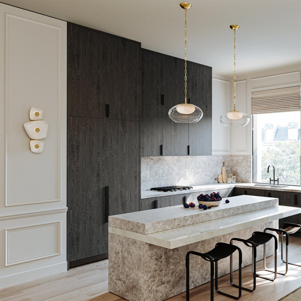 Clérachic alabaster wall sconce on the wall of a daylit kitchen with dark timber cabinetry and a marble island.