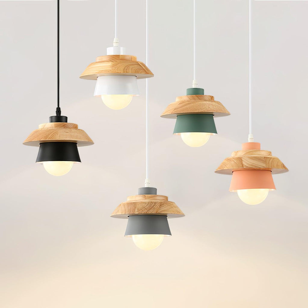 Five Clérachic pendants in black, white, green, grey and pink hang at different heights, each with a wood top and a bulb glowing inside.