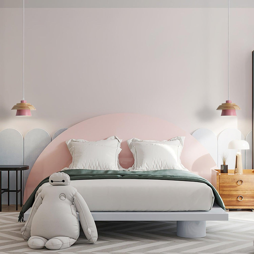 Two pink-shaded Clérachic pendants flank a pink arched headboard in a child-friendly bedroom with a large soft toy.