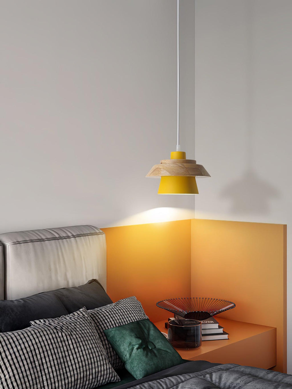 A yellow-shaded Clérachic pendant lights an orange corner by a bed with striped and dark-green cushions.