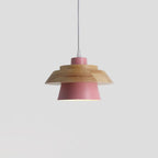 Pink metal shade under a layered natural wood top and a white cord, on a plain pale grey backdrop, from Clérachic.