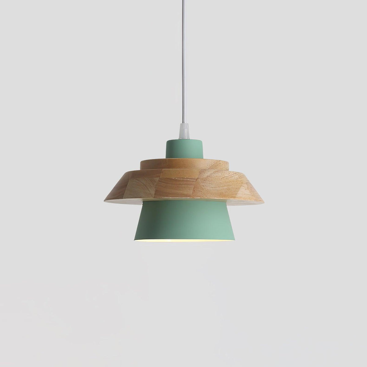 Green metal shade under a layered natural wood top and a white cord, on a plain pale grey backdrop, from Clérachic.