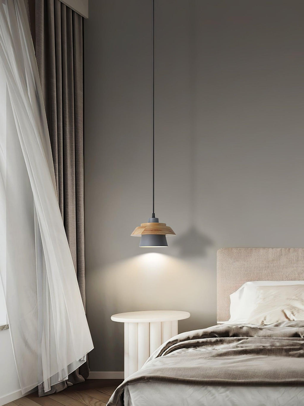 A black-shaded Clérachic pendant glows in a bedroom, beside a sheer curtain and a pale fluted round table.