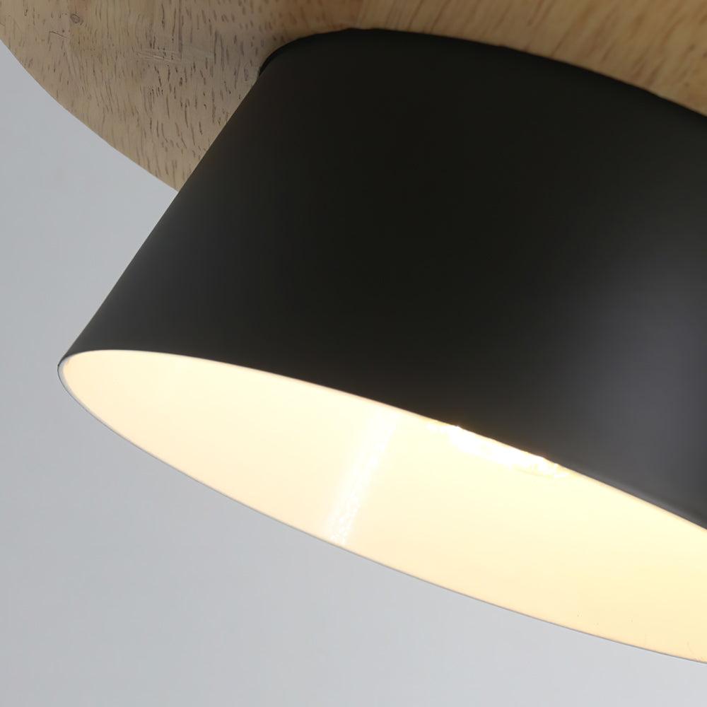 Close view of the black metal shade on this Clérachic pendant, its pale interior lit warm beneath the wood top.