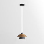 Grey-shaded Clérachic pendant with a layered wood top on a black cord and round black canopy, on a soft grey backdrop.