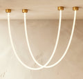 Clérachic gold-capped flexible LED chandelier loops in two glowing white arcs from a plaster ceiling corner.