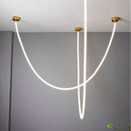 Clérachic gold-capped flexible LED chandelier arcs in three crossing white loops against a grey ceiling corner.