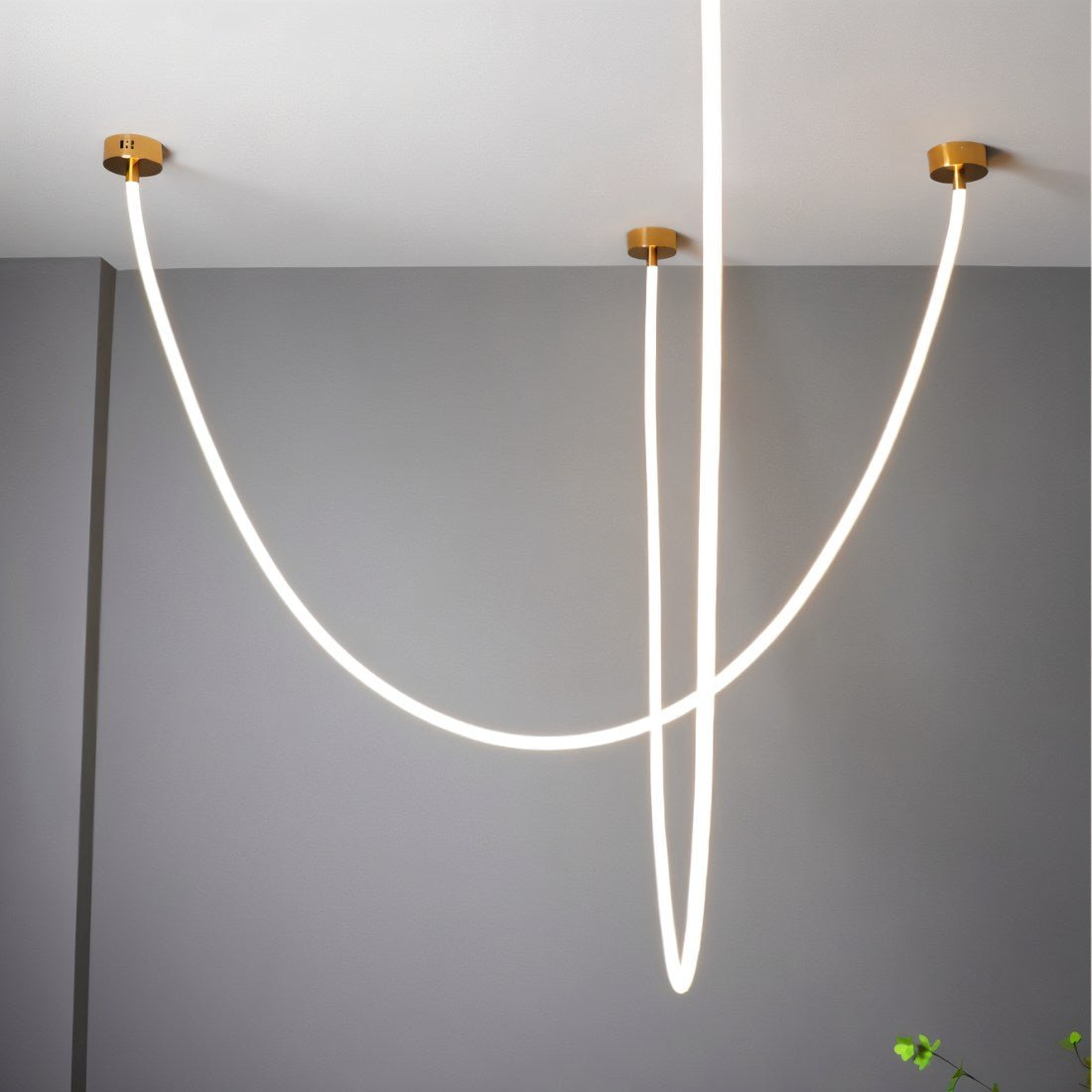 Clérachic gold-capped flexible LED chandelier arcs in three crossing white loops against a grey ceiling corner.