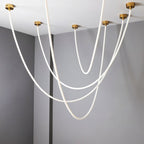 Clérachic gold-capped flexible LED chandelier arcs above a marble kitchen island beneath walnut cabinetry.