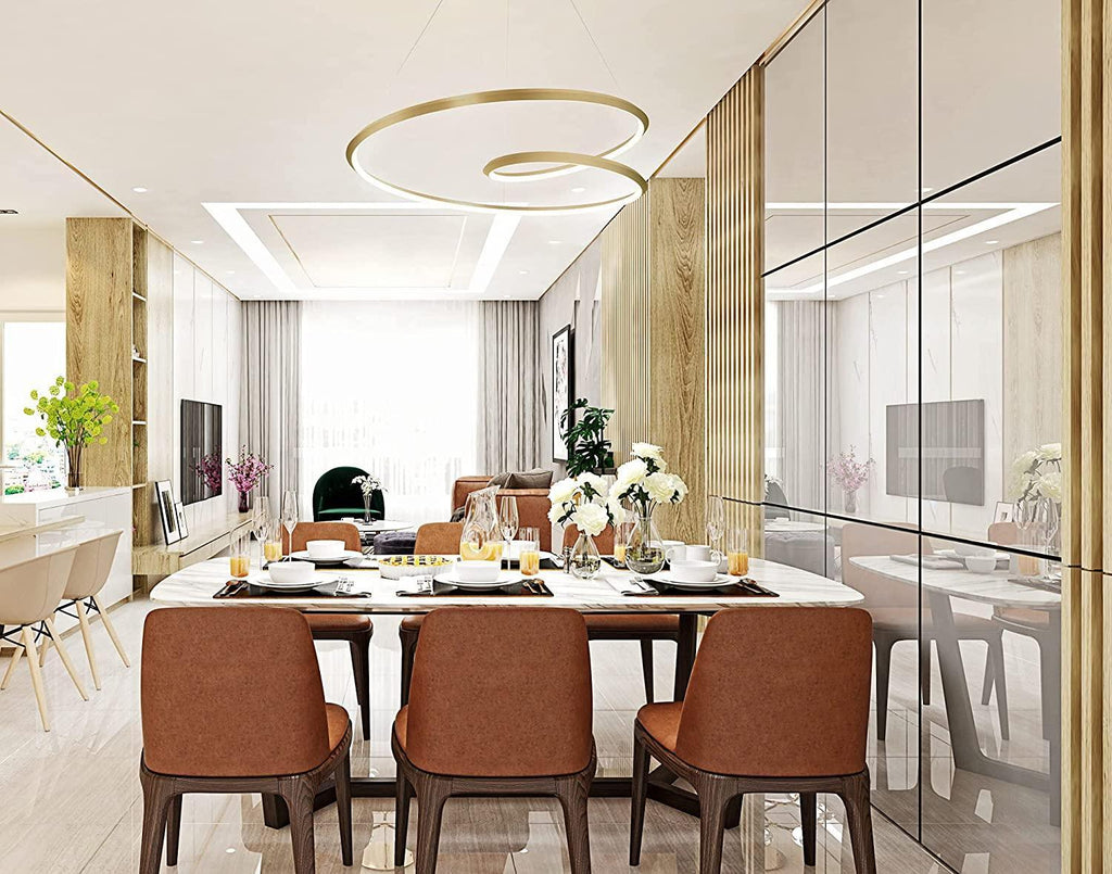 Wide view of this Clérachic gold ring chandelier above a dining table set with brown chairs and white flowers.