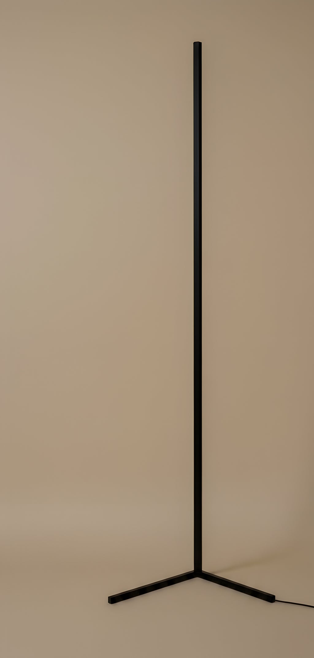The floor lamp switched off in daylight, showing the matte black square-section bar and the three flat blades of its base