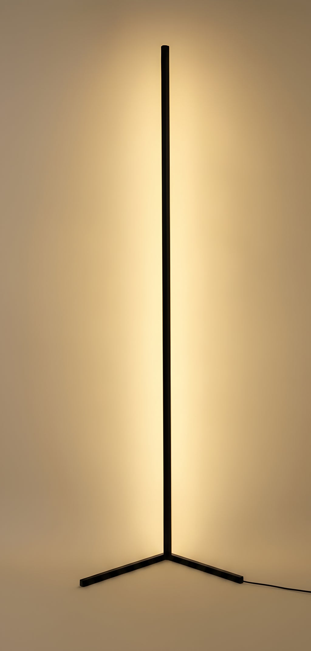 Clérachic Nordic LED floor lamp lit, its slim black bar throwing a soft warm wash onto the wall behind it from a low three-blade base