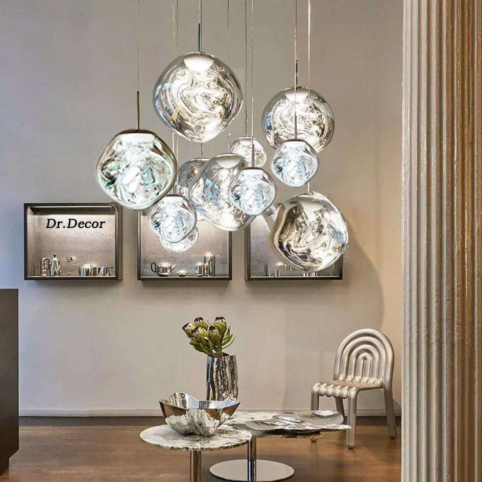 A cluster of Clérachic melt pendants in chrome hung above a marble table in a showroom.