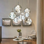 A cluster of Clérachic melt pendants in chrome hung above a marble table in a showroom.