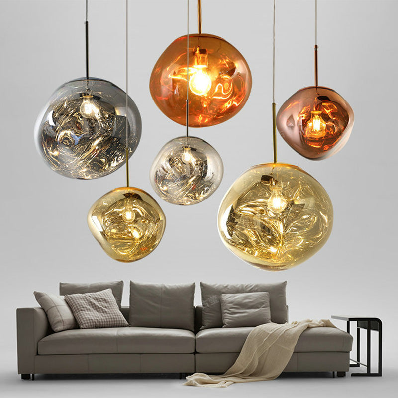 Six Clérachic melt pendants in mixed finishes hung at staggered heights above a grey sofa.