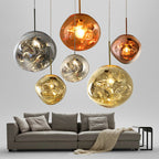 Six Clérachic melt pendants in mixed finishes hung at staggered heights above a grey sofa.