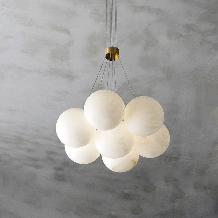 The Clérachic Norduvyd in a small cluster of oversized alabaster spheres, unlit against soft grey concrete.