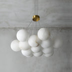 The Clérachic Norduvyd unlit from below, each alabaster globe hung at its own height on a clear suspension wire.