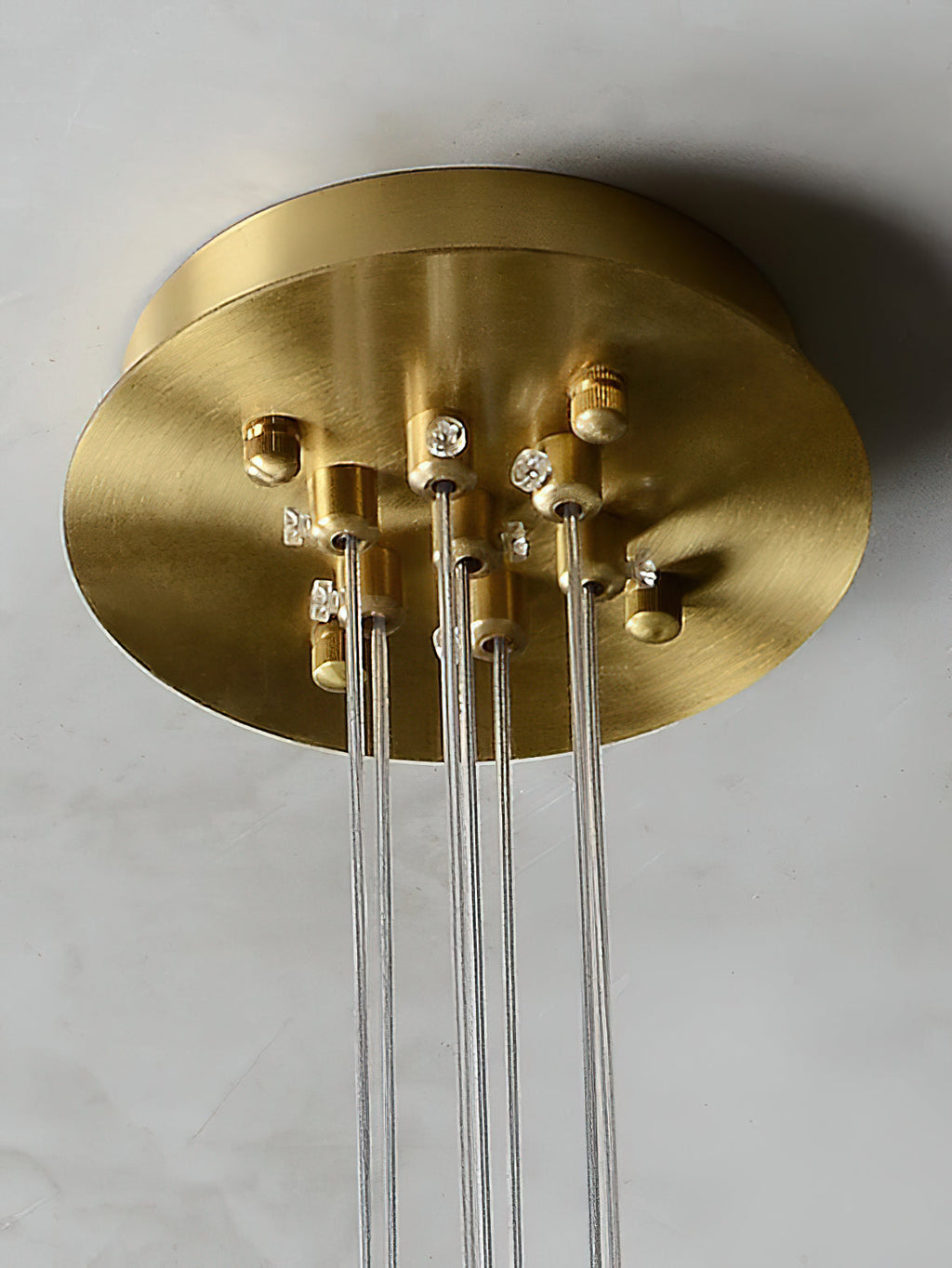 The Clérachic Norduvyd's brushed brass ceiling plate in detail, each suspension wire terminated around its edge.
