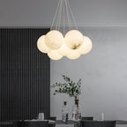 The Clérachic Norduvyd hangs above a dining table set with glass, against a dark fluted wall and pale plaster.