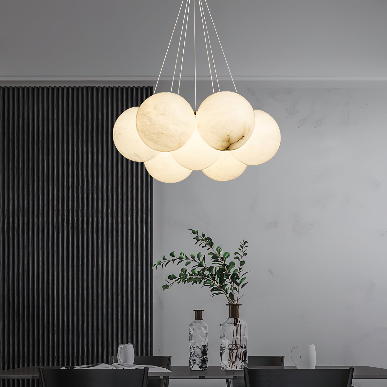 The Clérachic Norduvyd hangs above a dining table set with glass, against a dark fluted wall and pale plaster.