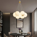 Clérachic lights a dining corner with the Norduvyd, its globes glowing beside a bookcase and a framed dune print.