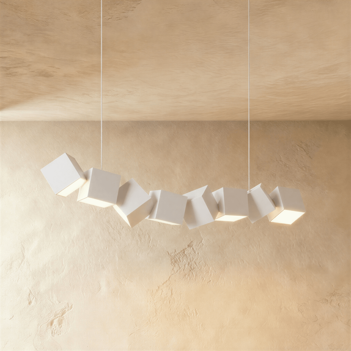 Clérachic row of eight tilted white aluminium cubes hung on white cables, lit from below against a plaster wall.
