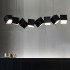 Clérachic eight black aluminium cubes hung at offset angles over a dark sideboard, each lit from below, on a grey wall.