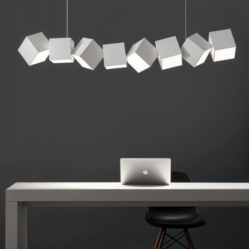 Clérachic eight white aluminium cubes in a tilted row above a white desk with a laptop and black chair on a charcoal wall.