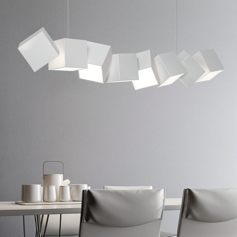 Clérachic eight white aluminium cubes at offset angles above a dining table set with white cups, with grey chairs.