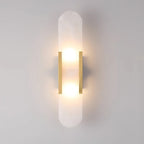 Clérachic Olraeia wall sconce in brass, both bulbs glowing behind the capsule alabaster panel on a pale grey wall