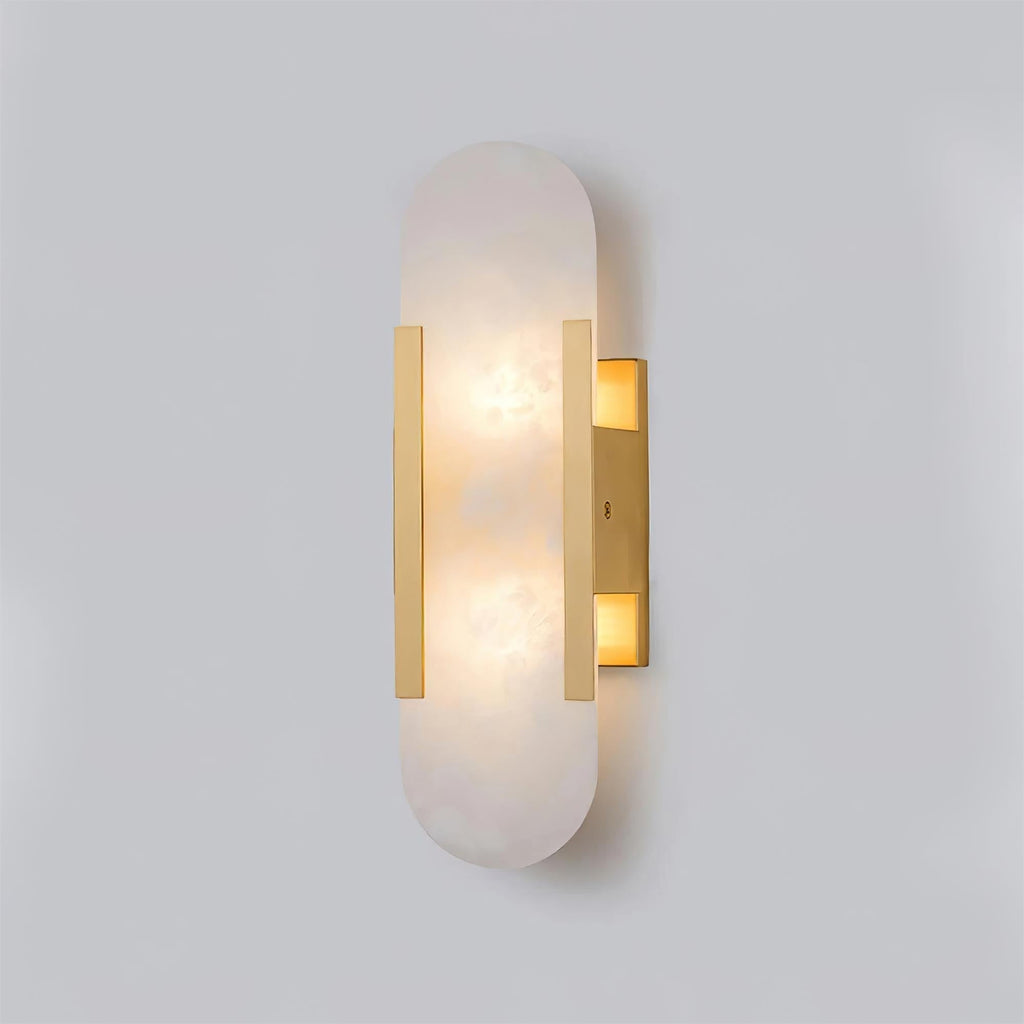 The Clérachic sconce angled to show the twin brass bars gripping the alabaster capsule, lit from within