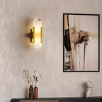 Clérachic sconce lit on a limewash plaster wall beside abstract art and a console of vases and dried stems
