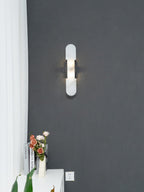 The Clérachic sconce with black bars on a charcoal wall, white sheer curtain and roses on the console beneath