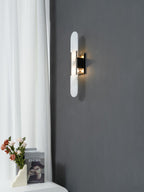 Clérachic sconce on a deep grey wall, its lit alabaster capsule set against a linen curtain and styled console
