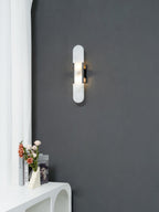 The Clérachic sconce seen at a distance on a charcoal wall, giving the full scale against a white curved console
