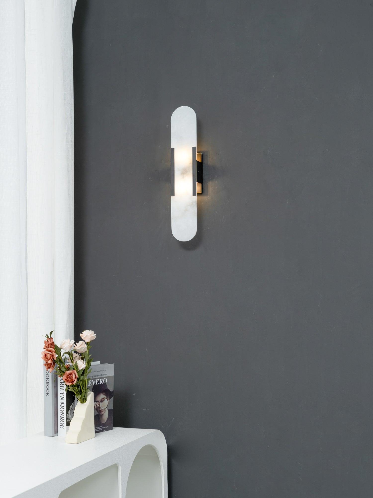 The Clérachic sconce seen at a distance on a charcoal wall, giving the full scale against a white curved console