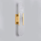 Clérachic sconce unlit in brushed brass on grey, showing the stone grain and the offset mounting block