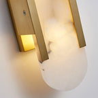 Clérachic sconce in close-up from below, the brushed brass channel and fixing screw against the veined stone