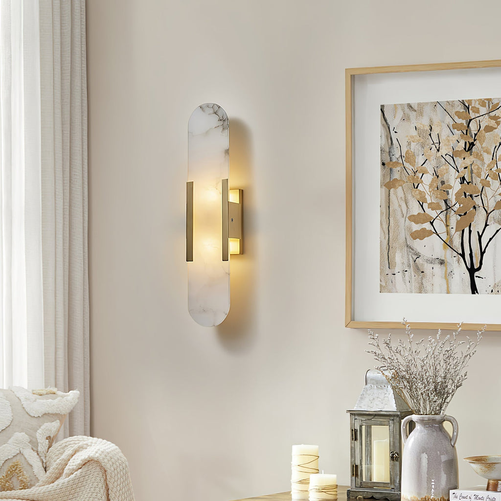 Clérachic sconce lit on a cream wall above a console of candles, a glass lantern and a stoneware jug